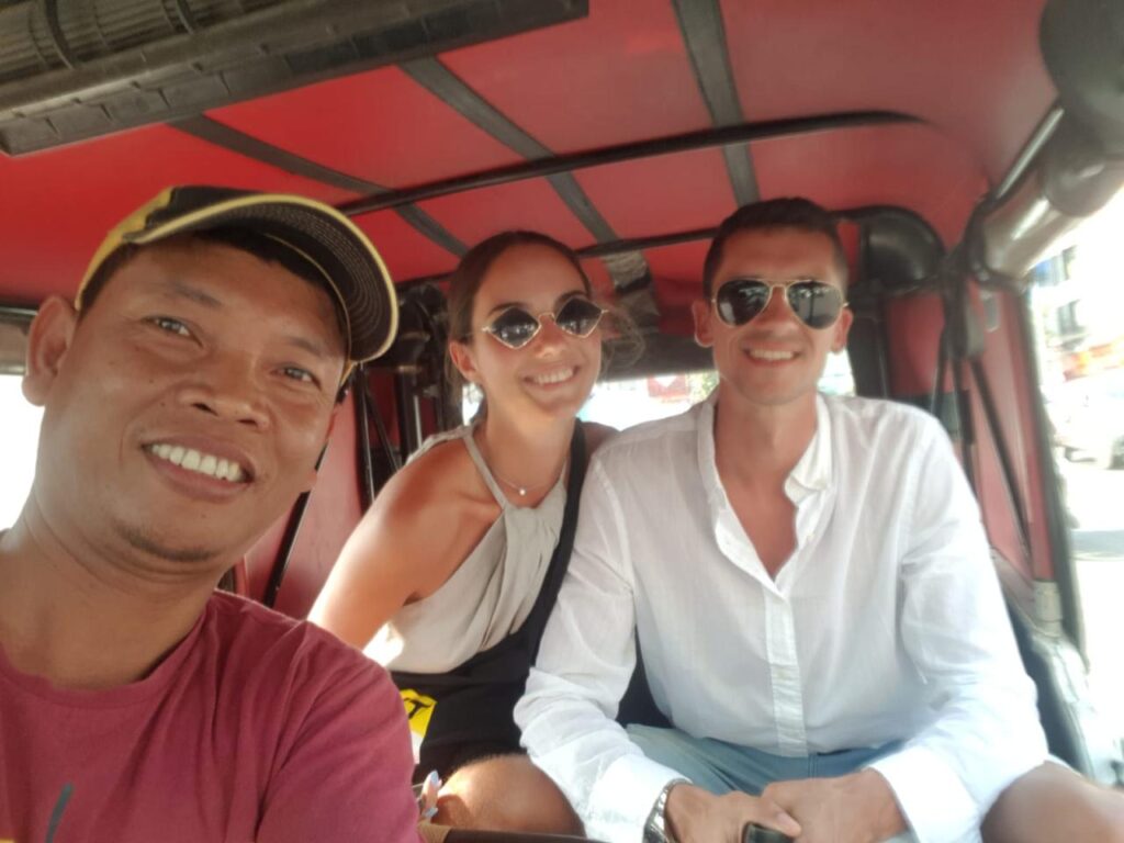 Bunna with two happy tourists inside his tuk-tuk in Phnom Penh, showcasing his friendly service and the authentic Cambodian travel experience.